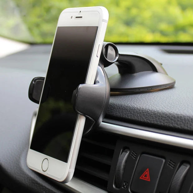 Black car dashboard phone mount with a suction cup base holding a smartphone in a vehicle.