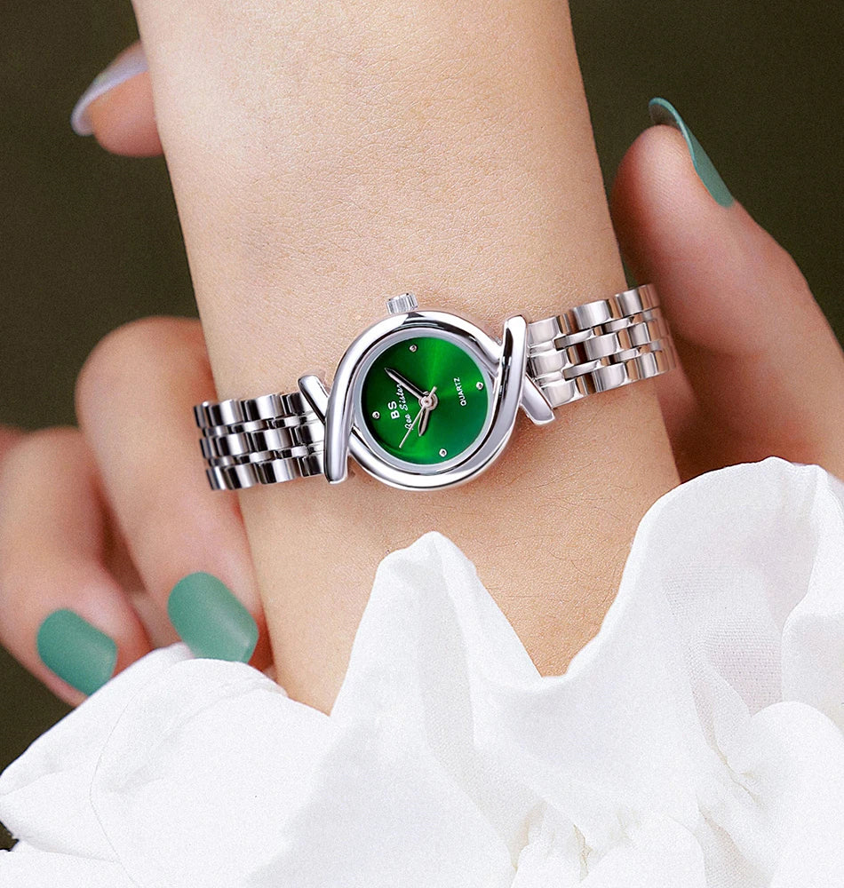 Women’s stainless steel quartz watch with a striking emerald green round dial and unique crossover silver bracelet.