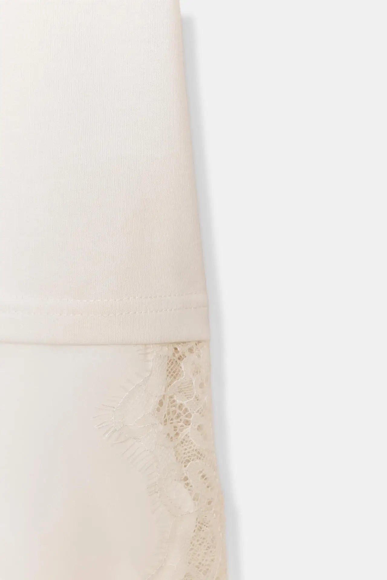 Cream-coloured top featuring delicate floral lace trim detail at the hem.