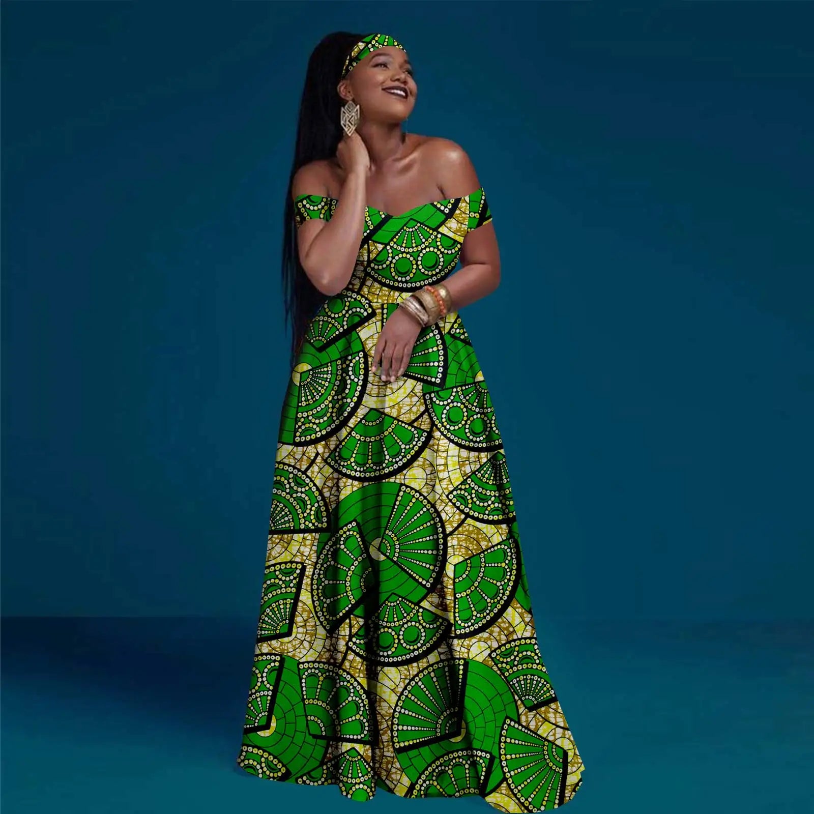 Woman wearing an off-shoulder, floor-length maxi dress in green and yellow with a fan pattern and matching headband.