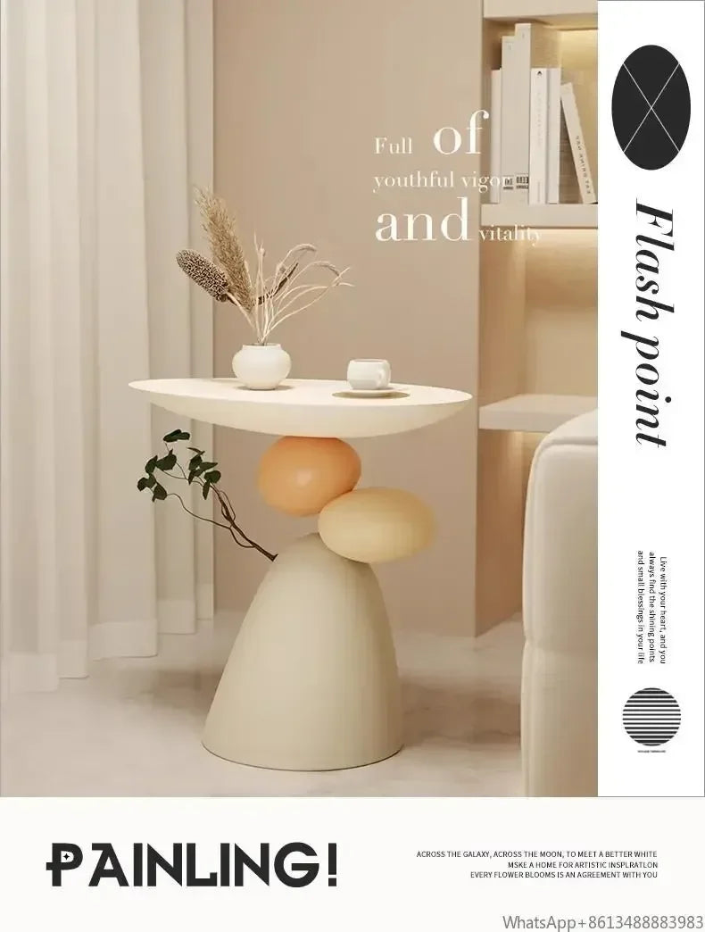Minimalist cream side table featuring a sculptural base with stacked rounded shapes and an oval tabletop.