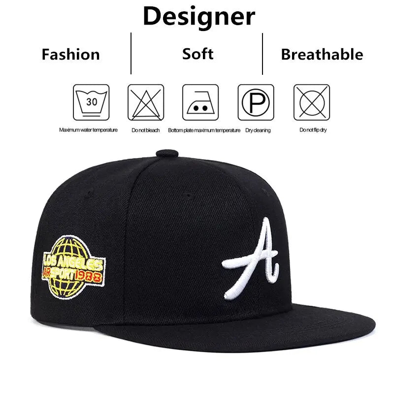 Black hip-hop baseball cap with white Gothic 'A' embroidery and a yellow global sports logo patch on the side.
