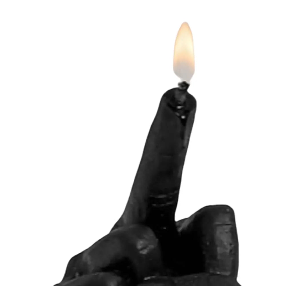 Black candle shaped like a hand making an offensive gesture, with a lit flame on the middle finger.