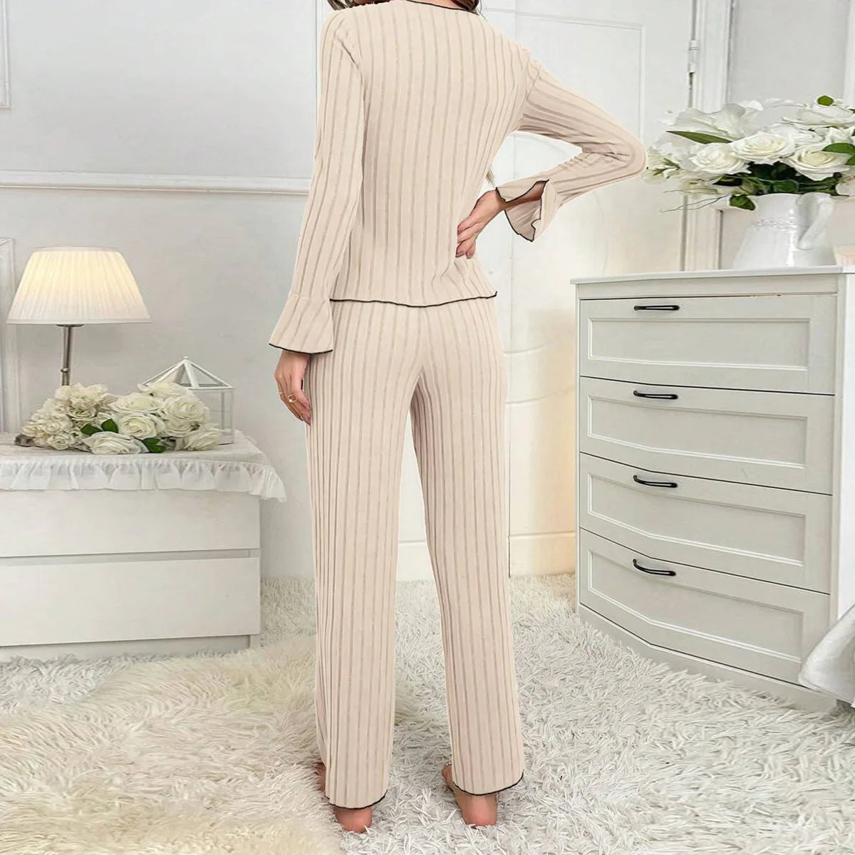 Beige ribbed loungewear set with long-sleeved top featuring flared cuffs and matching straight-leg trousers.