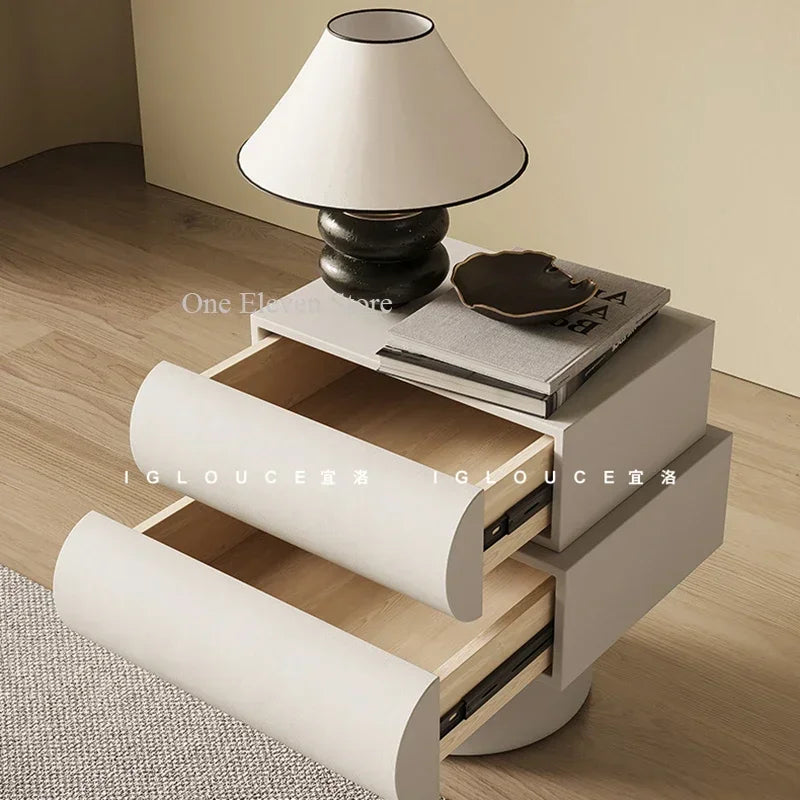 Modern white floating bedside table with two curved-front drawers, topped with a lamp and decor.