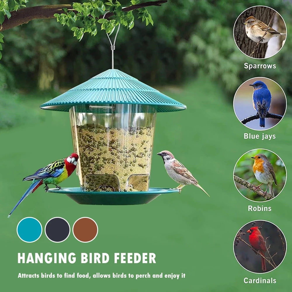 Teal hanging bird feeder with a clear, seed-filled reservoir, tiered roof, and perch tray in a garden setting.