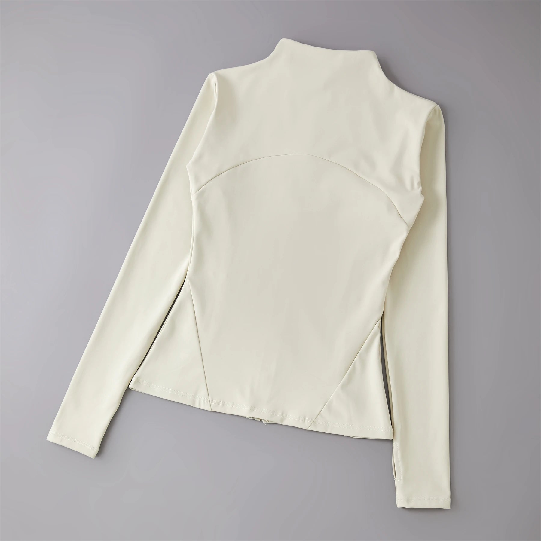 Cream-coloured long-sleeve athletic jacket with a mock neck, back seam detailing, and thumbhole cuffs.