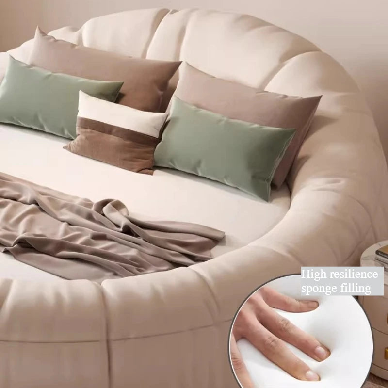 Modern cream minimalist circular bed frame with soft, cushioned upholstery and decorative sage and brown cushions.
