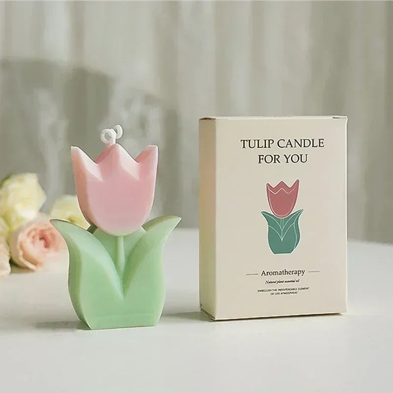 Pink and green tulip-shaped aromatherapy candle next to its matching cardboard gift box.