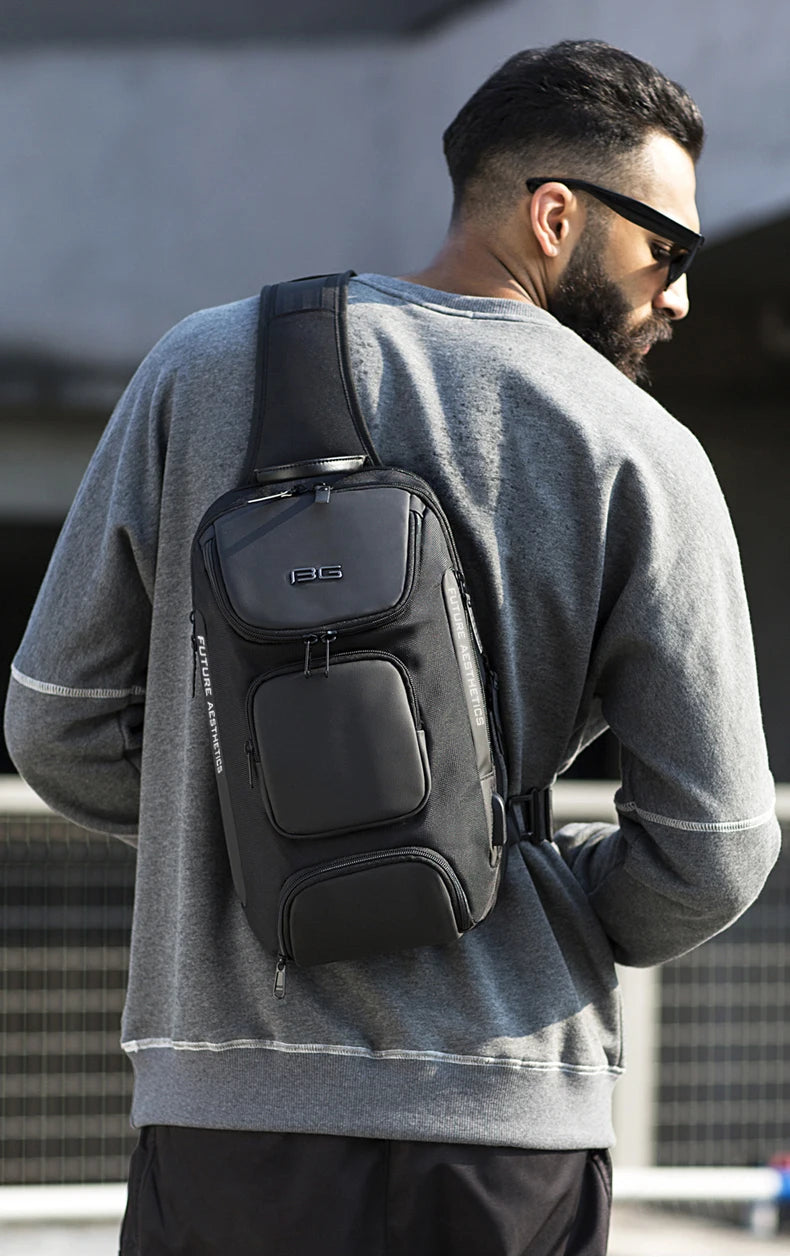 Man wearing a sleek black, multifunction crossbody bag with multiple zipped compartments, worn over a grey jumper.