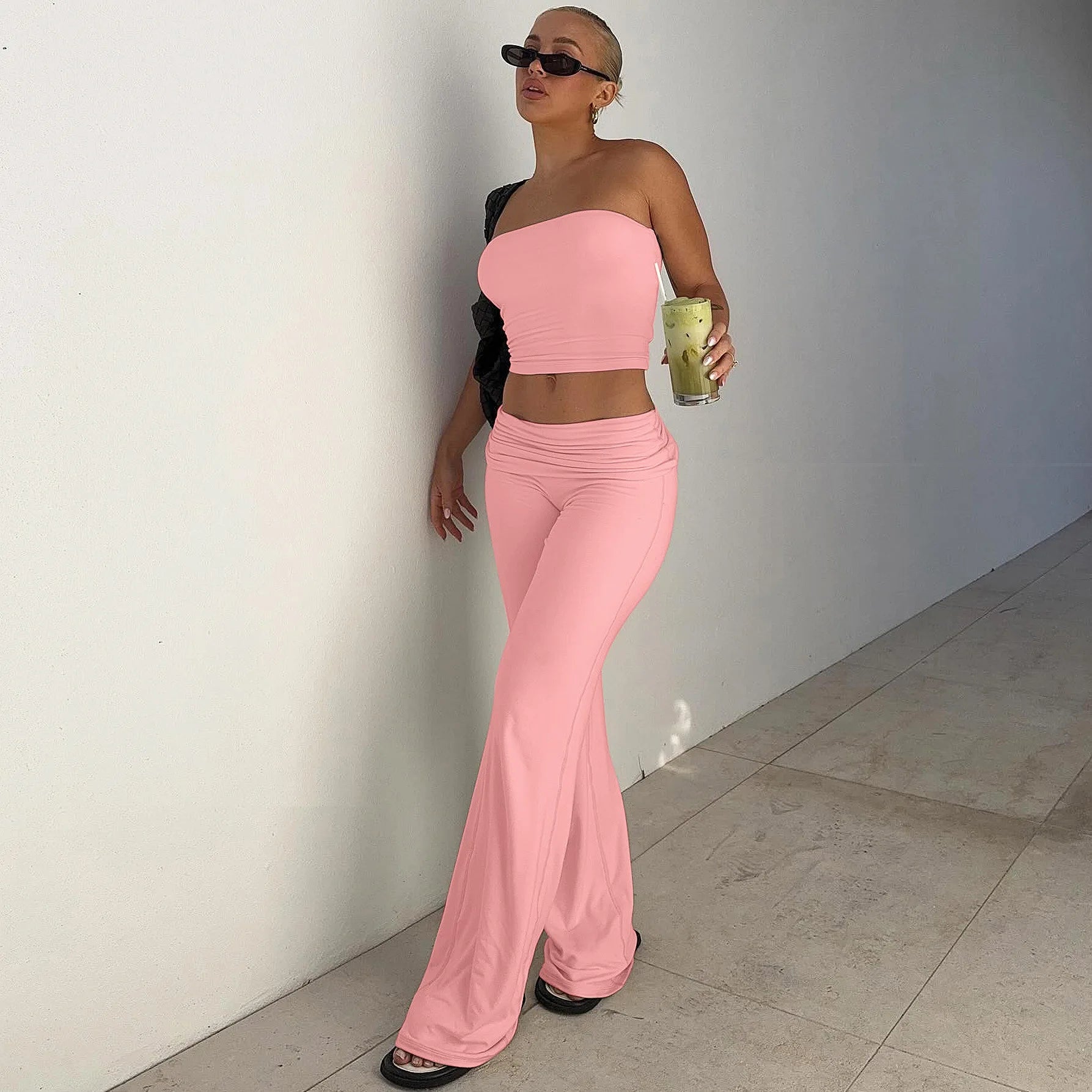 Pastel pink two-piece set featuring a strapless bandeau crop top and high-waisted, flared trousers.