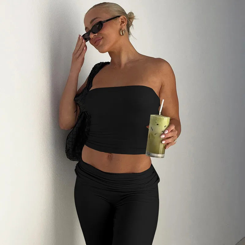 Woman wearing a black bandeau crop top and matching high-waisted leggings with a ruched waistband.