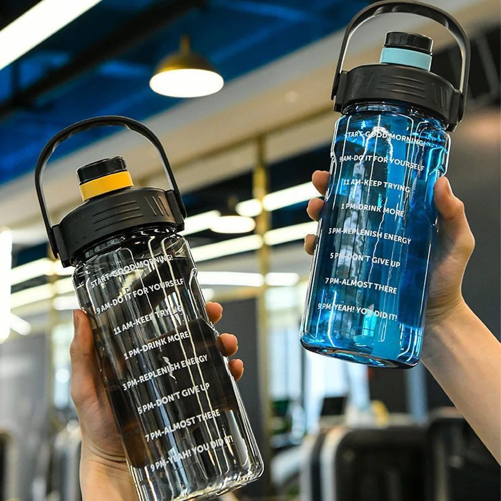Two translucent, 1-litre water bottles in blue and black with motivational time markers and carry handles.