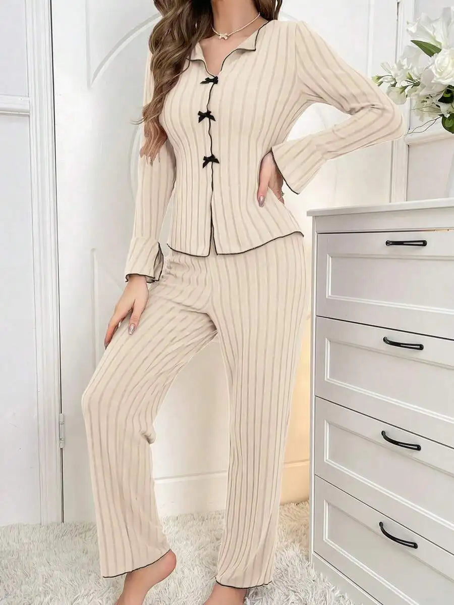 Beige ribbed two-piece lounge set with black trim, button-front top with small bows, and matching wide-leg trousers.