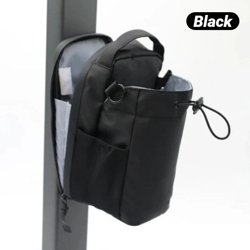 Black drawstring bag with a grab handle, side pocket, and zip-open light grey interior, hanging on a post.