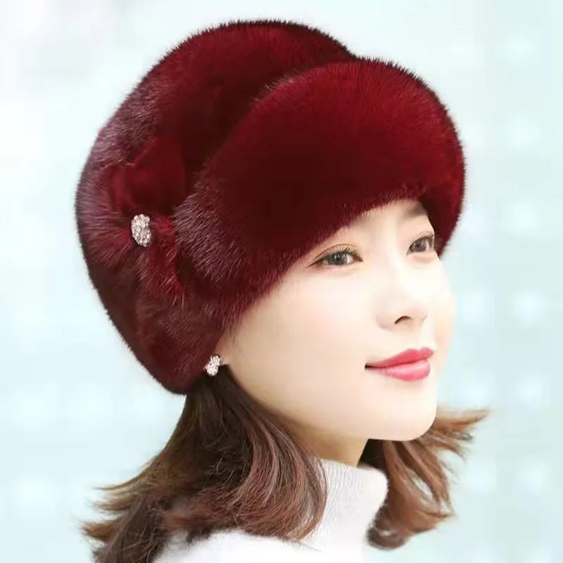 Elegant deep red faux fur winter hat with a decorative side bow and sparkling jewel detail.