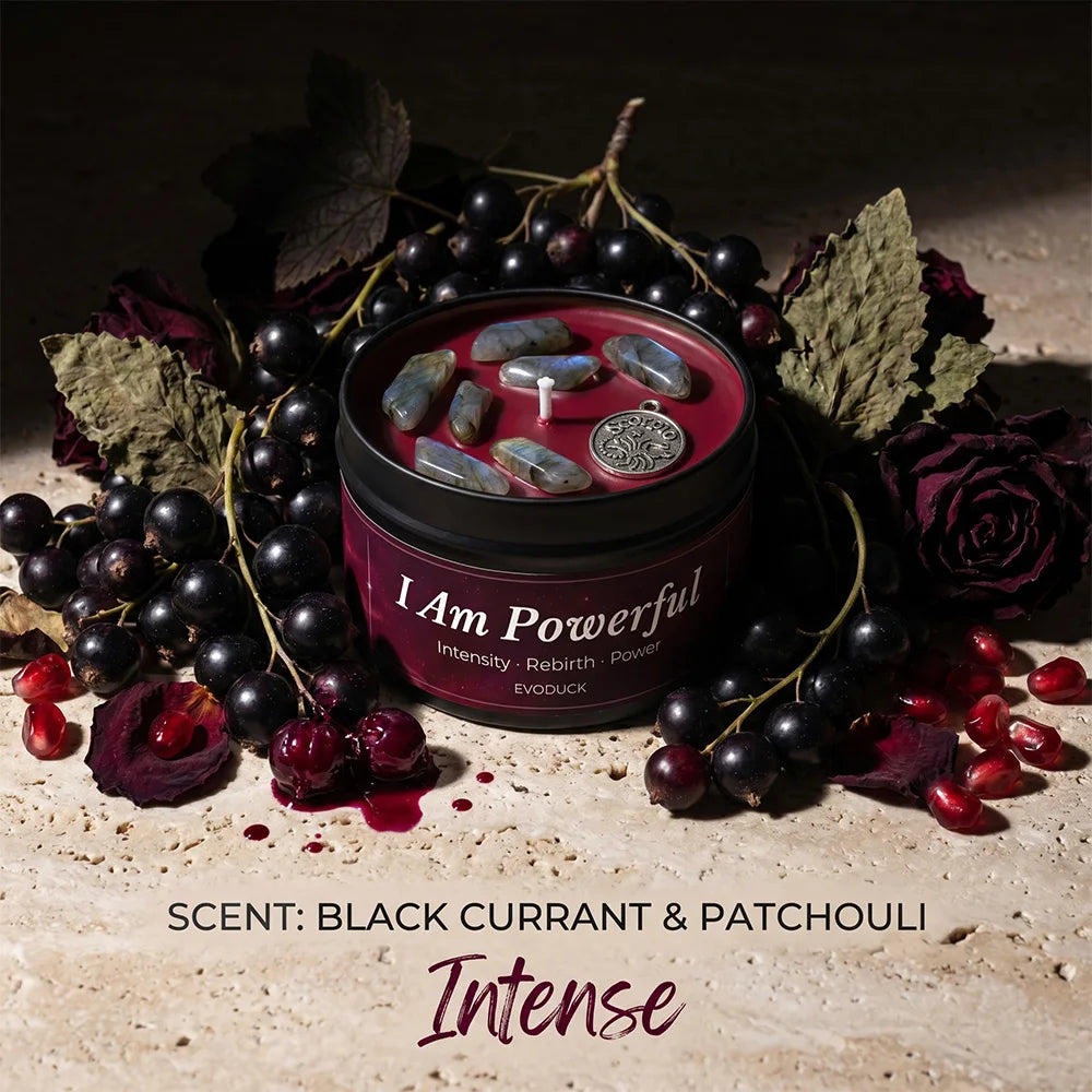 "I Am Powerful" scented candle in black tin, topped with crystals and a charm, surrounded by blackcurrants and roses.