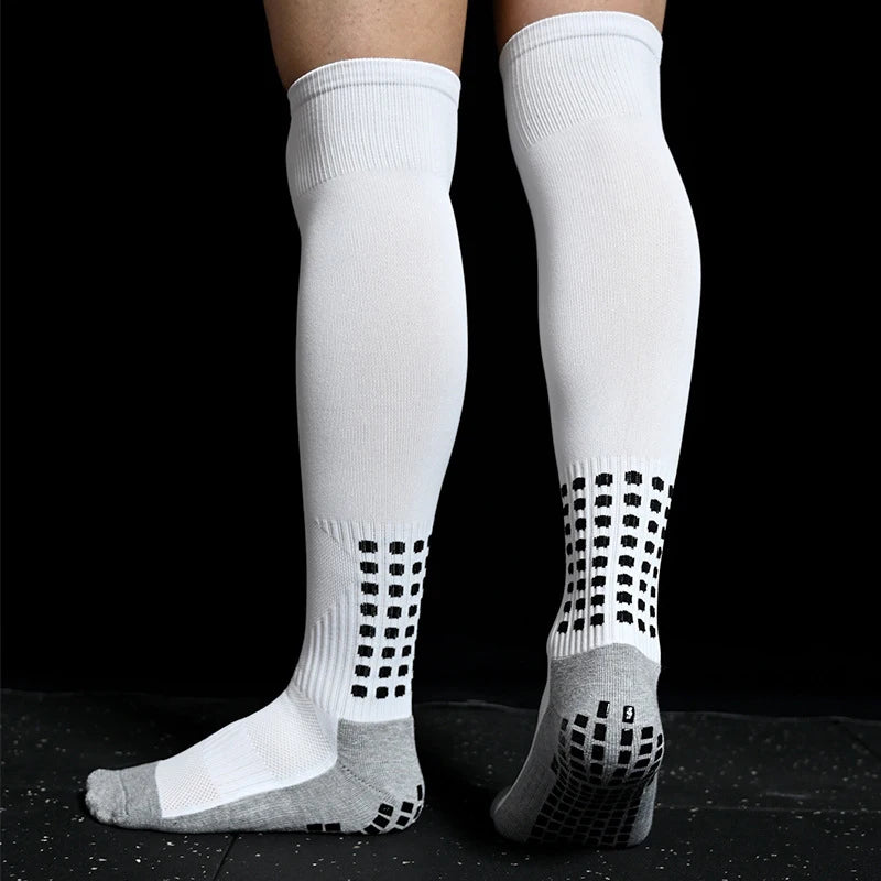 White knee-high sports socks with grey heels and black grip pads on the soles and ankles for non-slip performance.