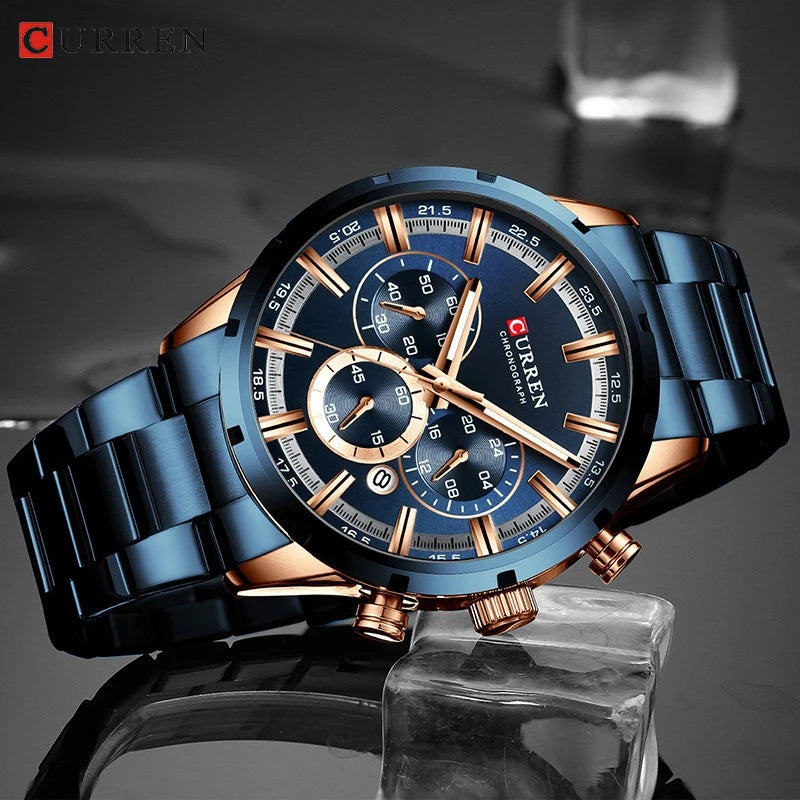 CURREN blue and rose gold chronograph wristwatch with a round dial and metal link band on a dark surface.