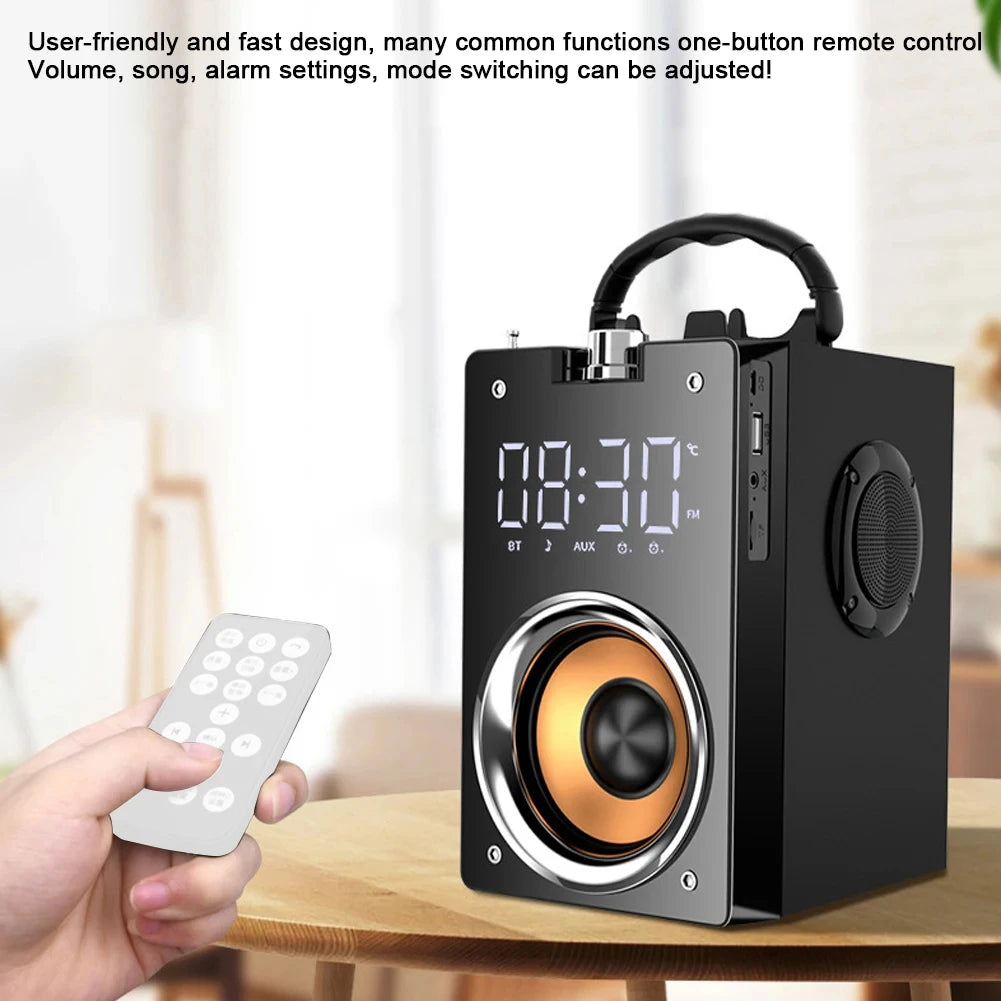 Portable black wireless speaker with digital clock, carry handle, gold speaker cone, and a handheld remote control.
