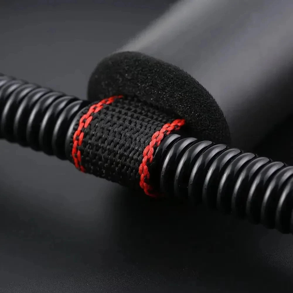 Close-up of a black exercise resistance bar with a textured grip, black foam padding, and red contrast stitching.