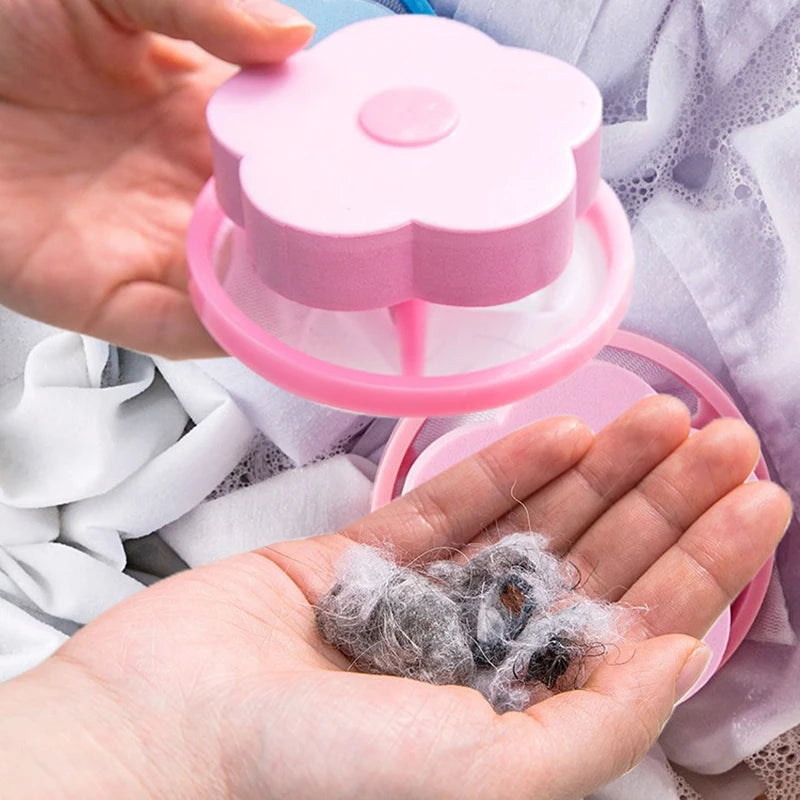 A hand holding a pink, flower-shaped laundry lint catcher containing grey fluff removed from clothes.