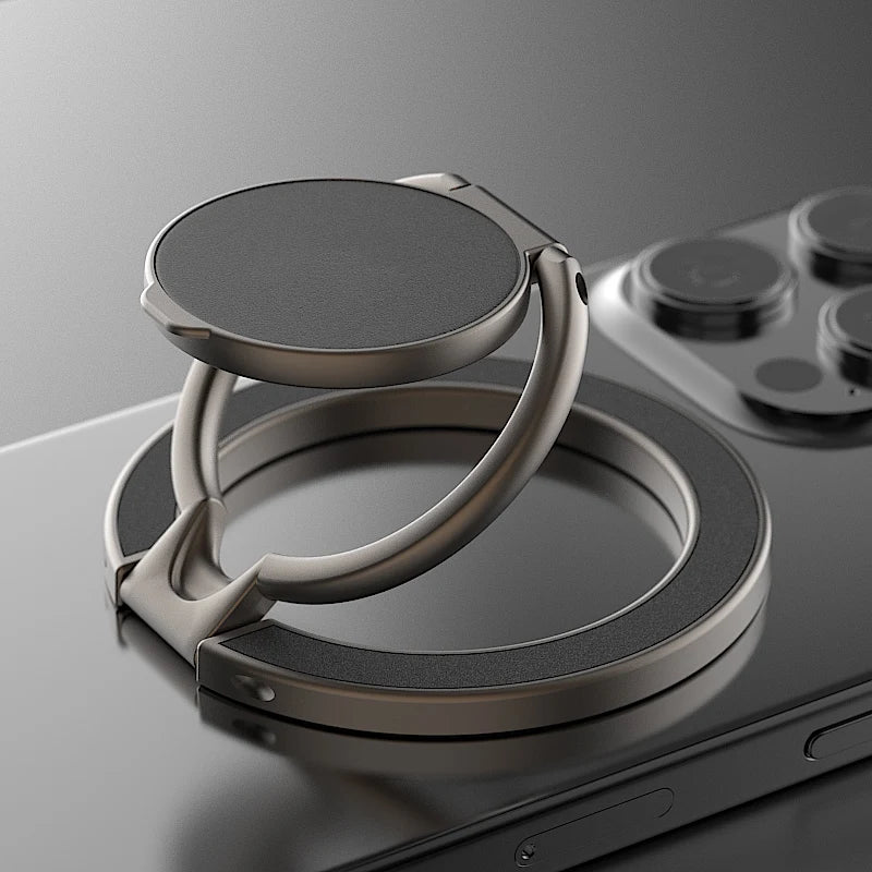 Grey circular magnetic phone ring holder with a foldable kickstand design attached to the back of a smartphone.