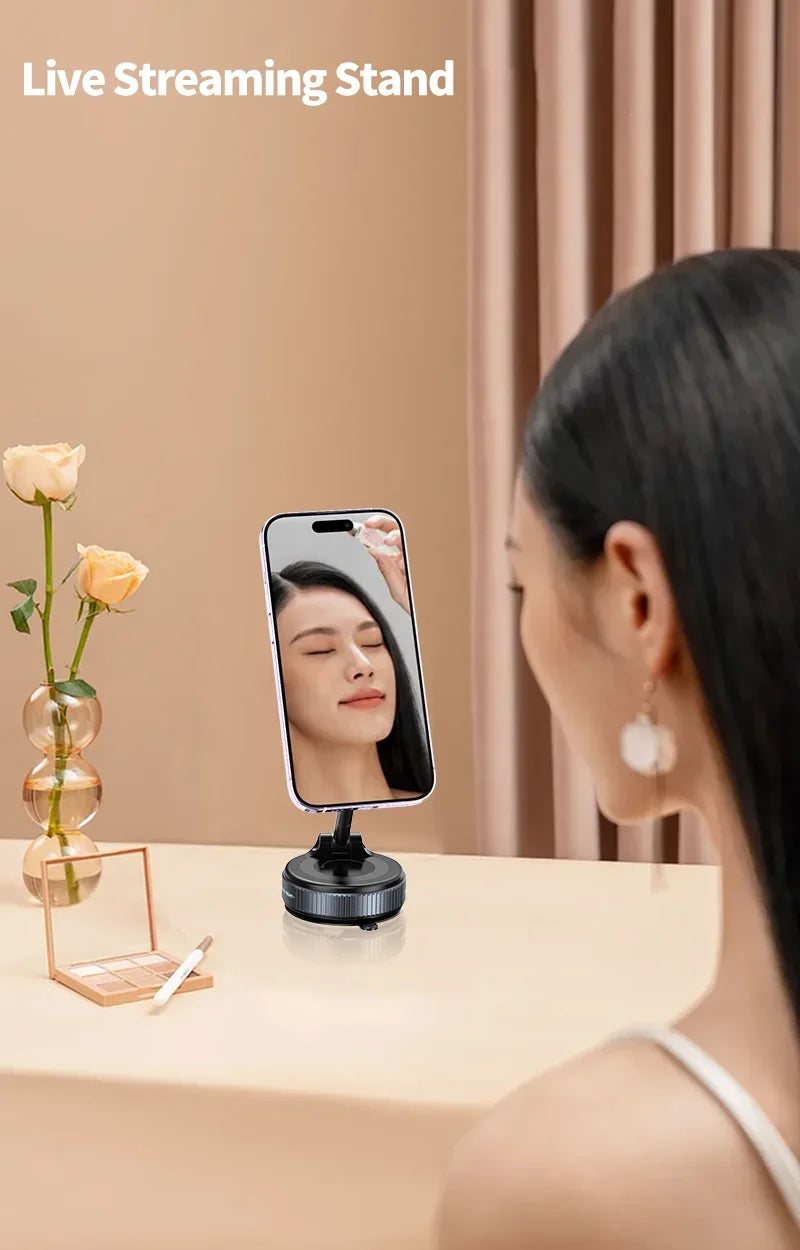 A sleek, black magnetic smartphone stand on a desk, holding a phone vertically for a person to view themselves.