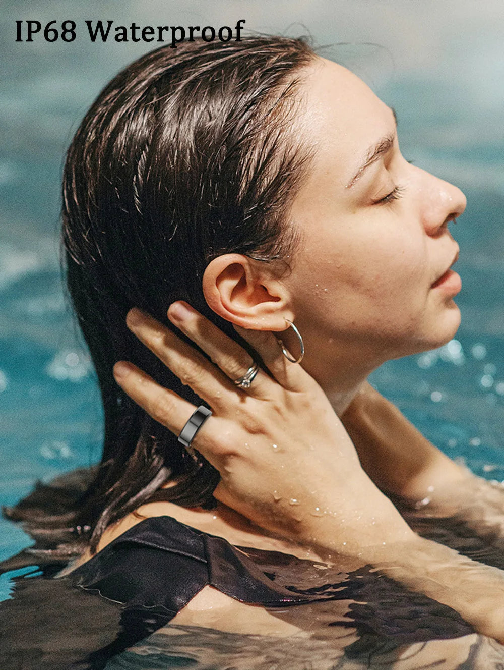 Woman wearing a sleek, dark grey waterproof smart fitness ring whilst swimming.