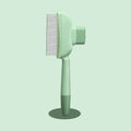 A sage green pet grooming comb with fine metal teeth, standing upright on a matching circular base.