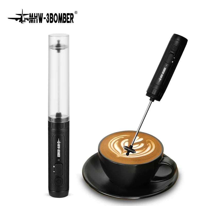Black handheld electric milk frother with a protective cover, shown frothing a cup of coffee with latte art.