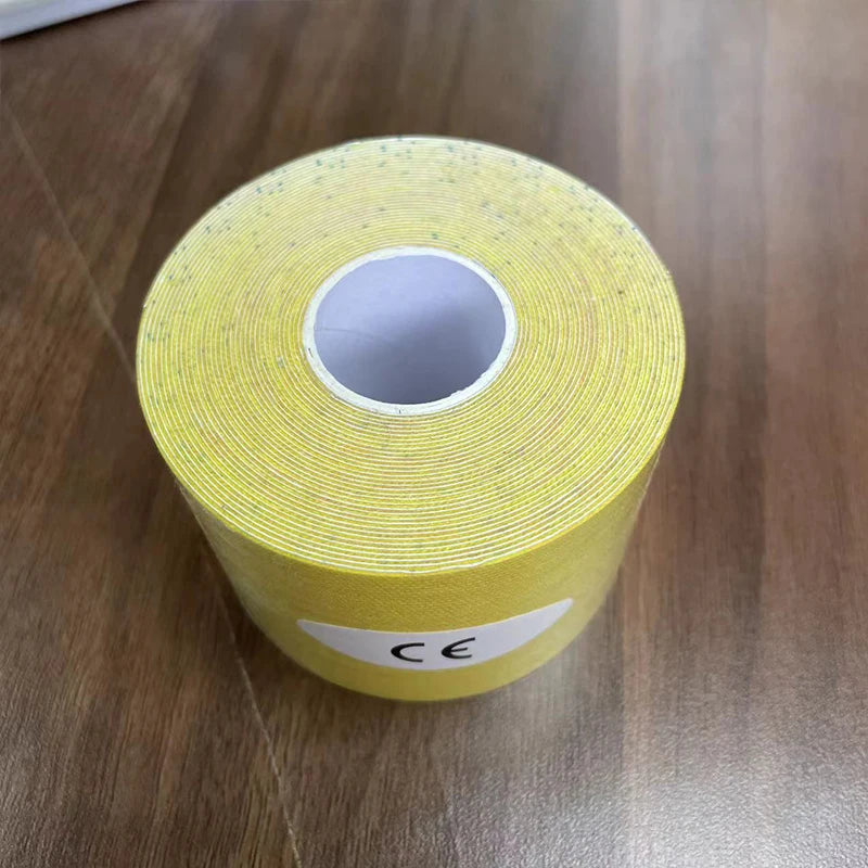 A roll of yellow kinesiology tape with a speckled texture and a CE-marked label, sitting on a wooden surface.