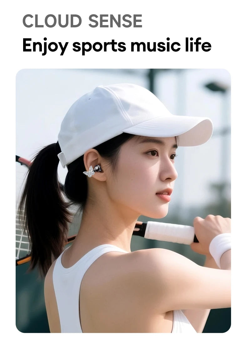 A person wearing a white baseball cap and silver butterfly-shaped wireless earbuds while holding a tennis racket.