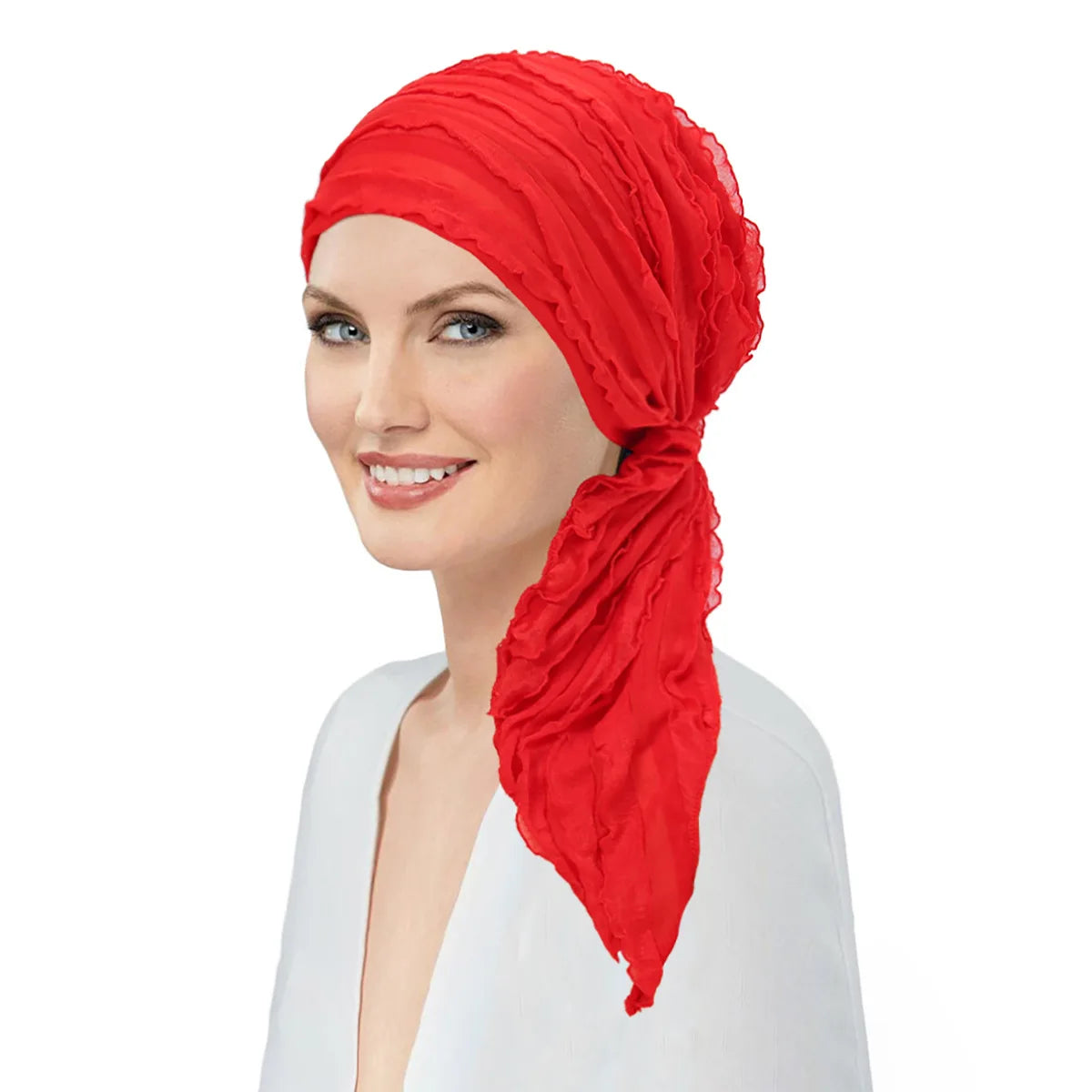 A smiling woman wearing a vibrant red pre-tied ruffled turban head wrap with a side drape.