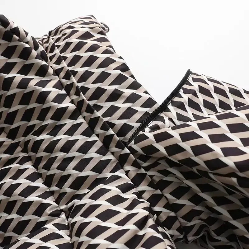 Close-up of a padded jacket featuring a black, white, and beige geometric diamond pattern with a central zip detail.