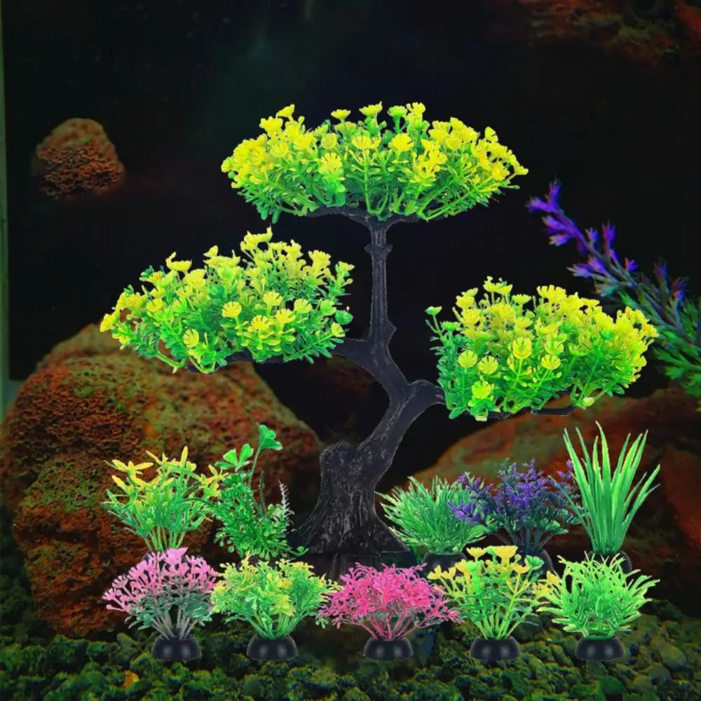 Artificial aquarium set with a central yellow-green tree and various small, colorful plastic plants on a dark base.