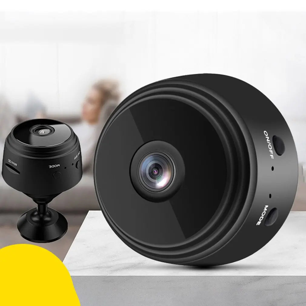 Small black circular plastic wireless security camera with a camera lens and side buttons for On/Off and Mode.