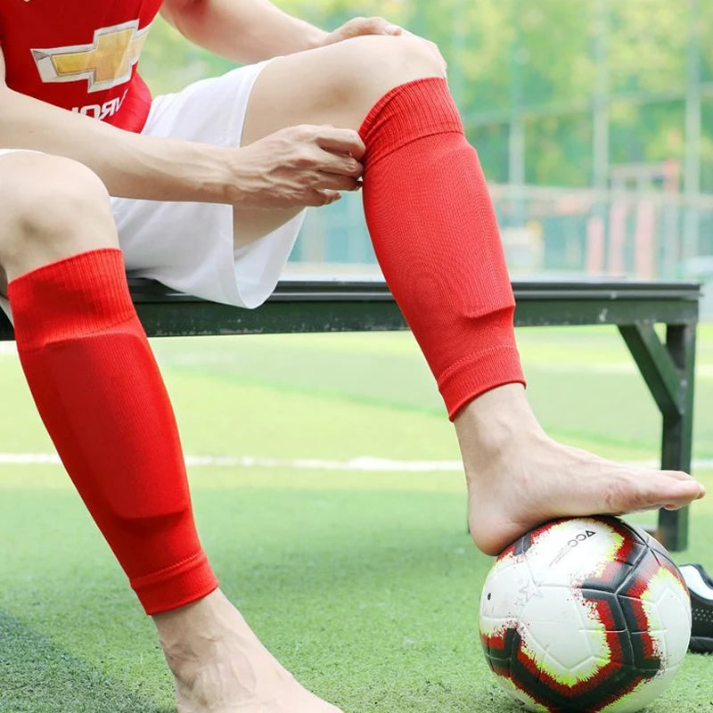 Red football shin guard sleeves worn on lower legs, designed for comfort and protection during sports.