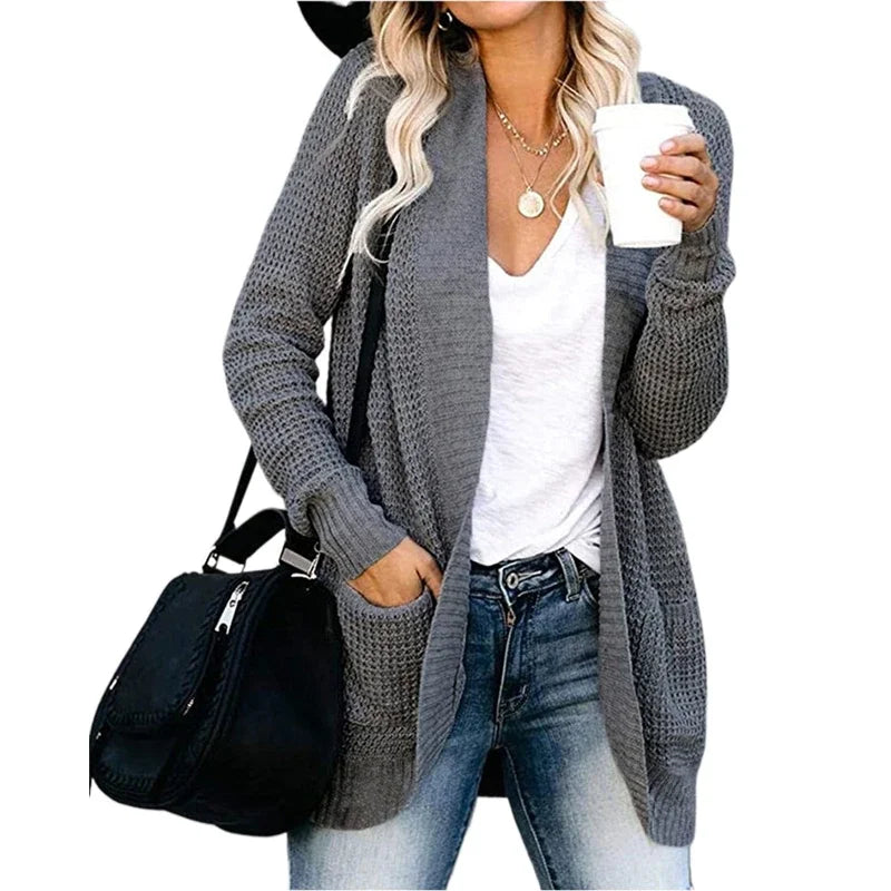 Dark grey open-front knitted cardigan sweater with front pockets, worn over a white top.