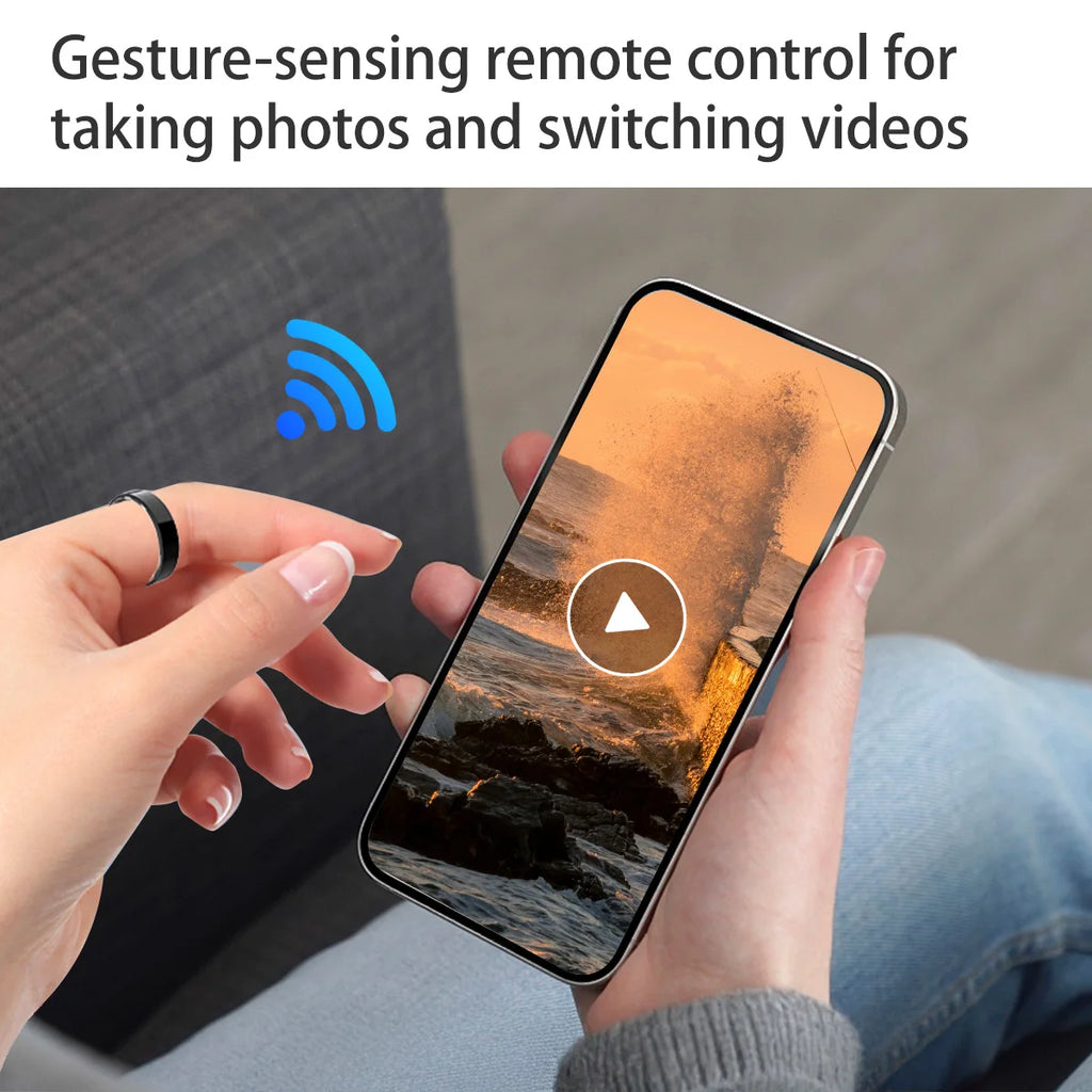A person wearing a sleek black smart health ring, using gesture control to play a video on their smartphone.
