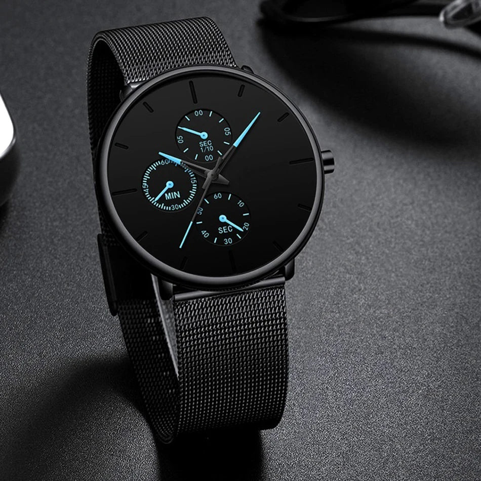 Ultra-thin men's watch in matte black with a stainless steel mesh strap, black dial, and glowing blue hands.