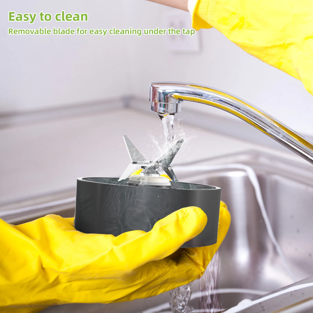 A person in yellow rubber gloves washes a grey circular blender blade assembly under a kitchen faucet.