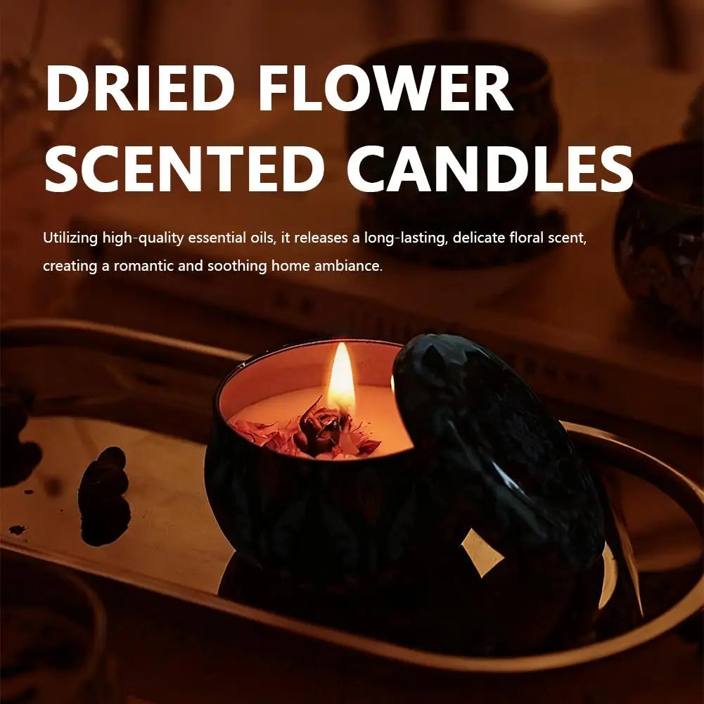 A lit, cream-coloured scented candle with dried flowers in a dark, patterned jar with a matching lid on a gold tray.