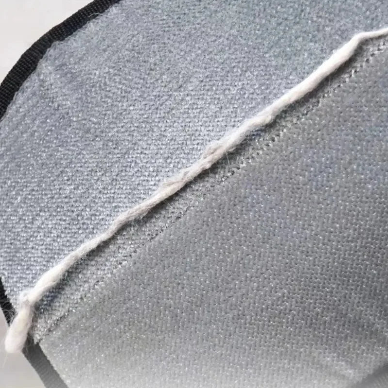 Close-up of a grey, felt-like fabric surface with a single, coarse white thread running diagonally across it.