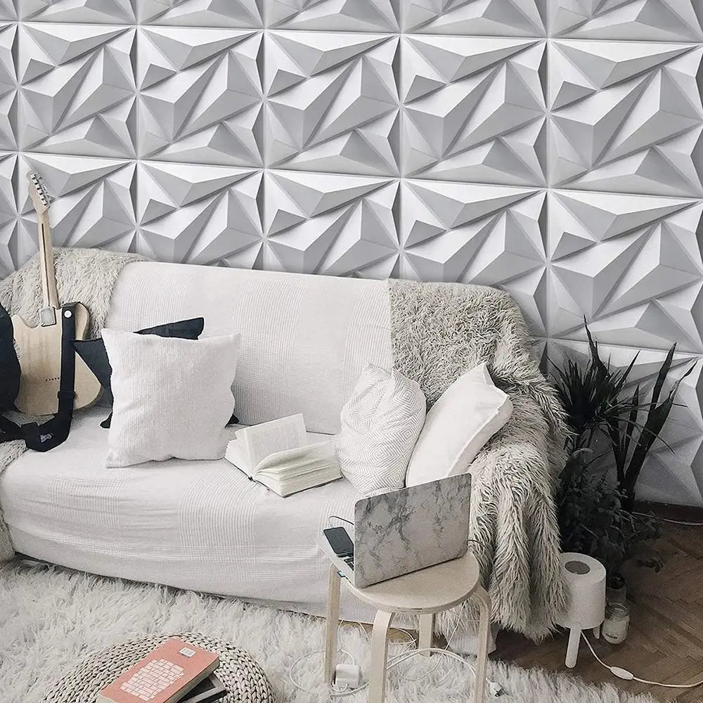 White 3D diamond-patterned decorative wall panels behind a cosy sofa in a modern, neutral-toned living room.