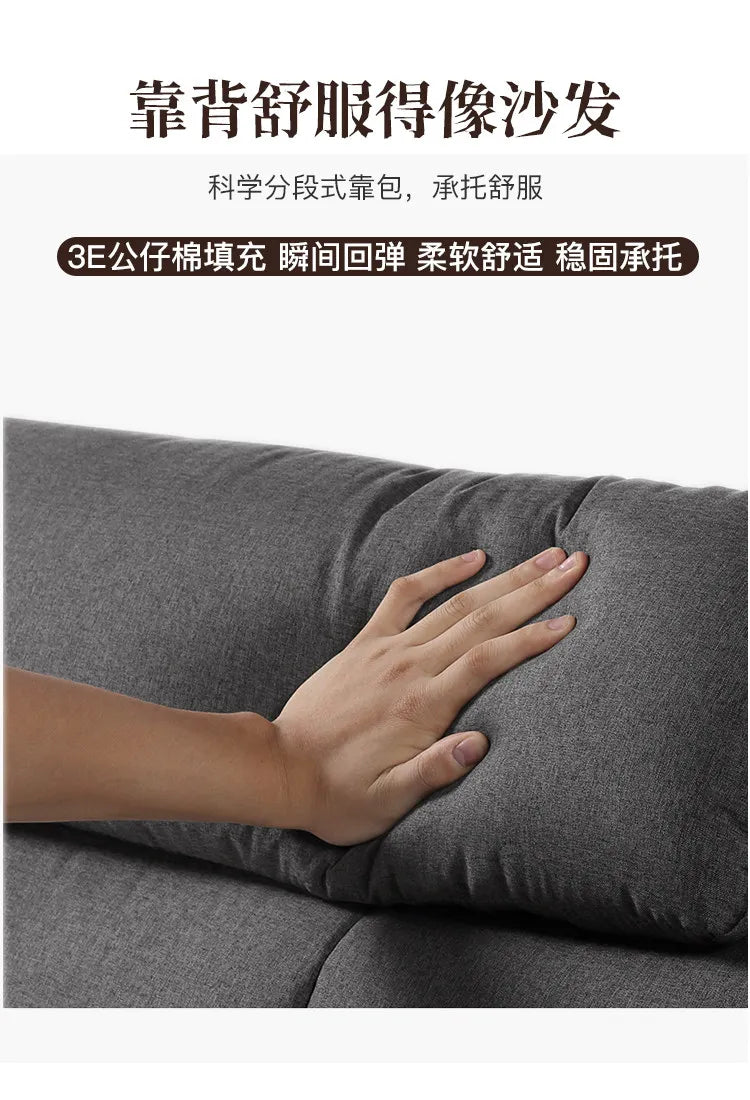 Close-up of a hand pressing into the soft, grey fabric upholstery of a modern bed headboard.