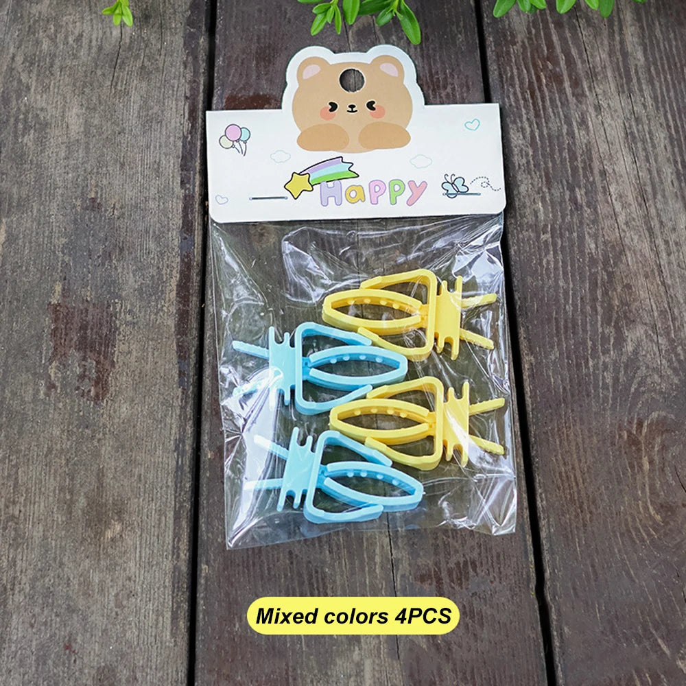A pack of 4 pastel yellow and blue plastic hair clips on a bear-themed card, resting on a wooden surface.