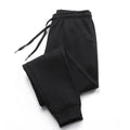 Black joggers featuring an elasticated drawstring waistband, side pockets, and cuffed ankles in a comfortable style.