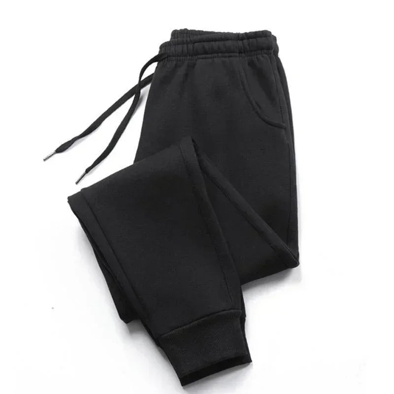 Black joggers featuring an elasticated drawstring waistband, side pockets, and cuffed ankles in a comfortable style.