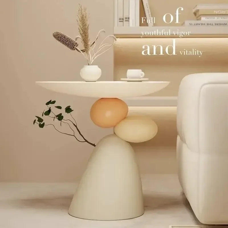 Minimalist cream sofa side table with a sculptural, layered stone-look base featuring soft peach and beige tones.